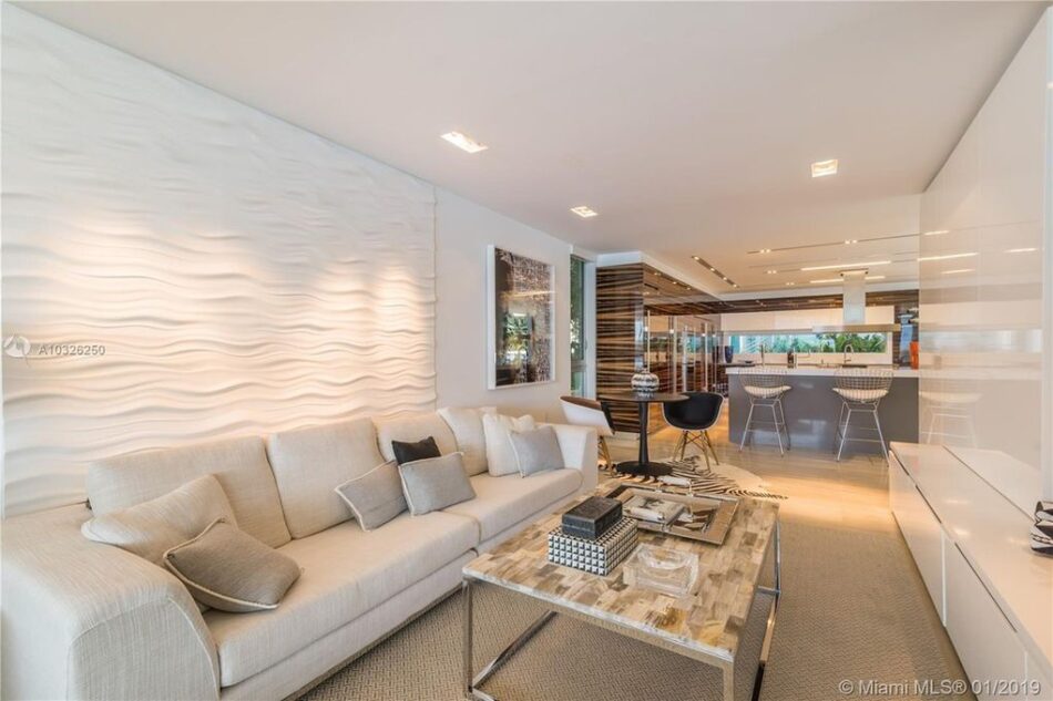 Modern living room with wavy accent wall and neutral sofa set.