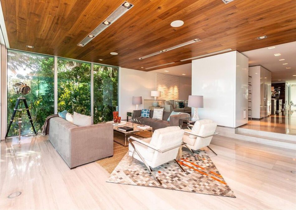 Modern living room with wood ceiling, glass walls, and cozy seating.
