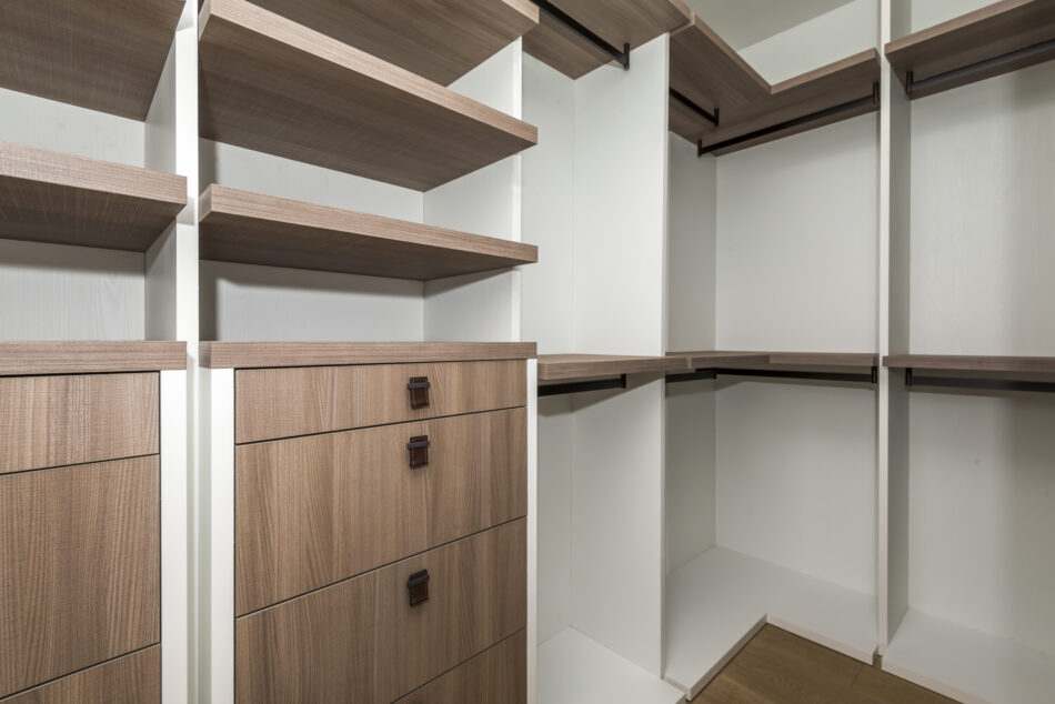 Corner walk-in closet with open shelving and wood drawers.