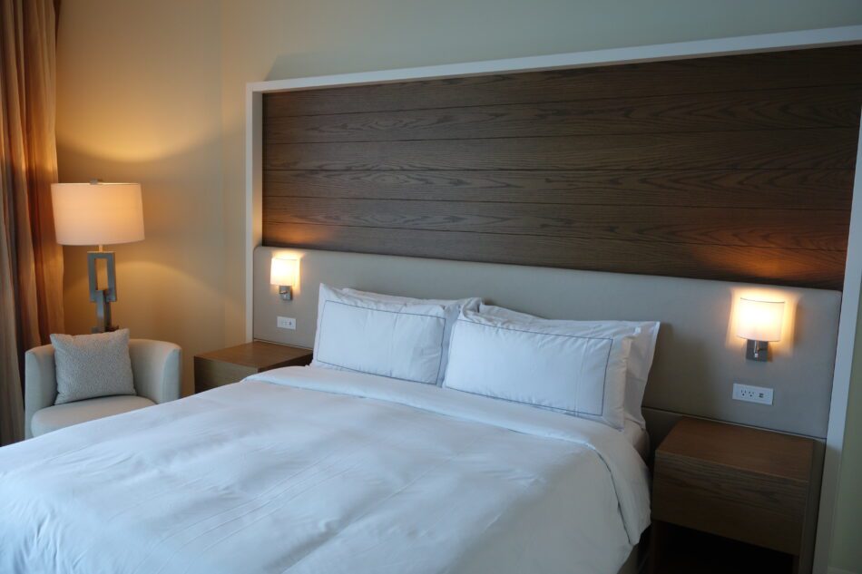 Cozy bedroom with wood panel headboard and warm ambient lighting.