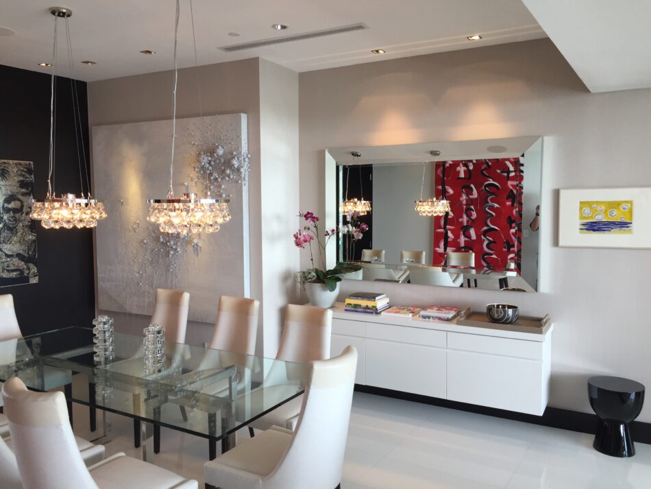 Elegant dining room with glass table and crystal chandeliers.