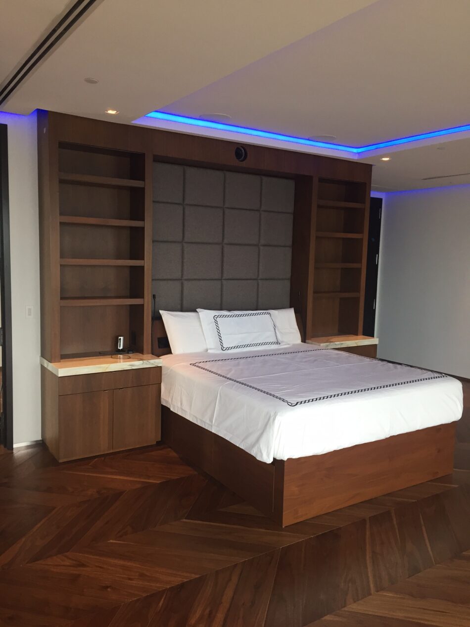 Custom bed with upholstered headboard and built-in wood shelving.