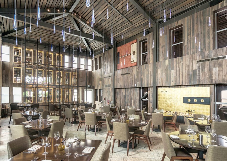 Rustic dining room with dark wood walls and tall wine display.