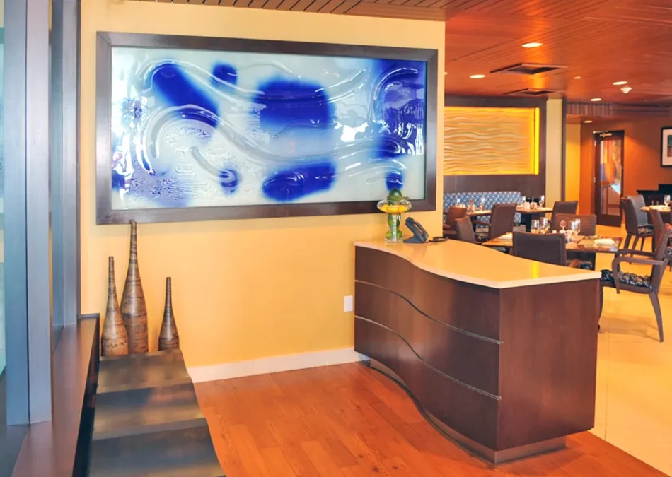 Curved wood reception desk under a large blue abstract artwork.