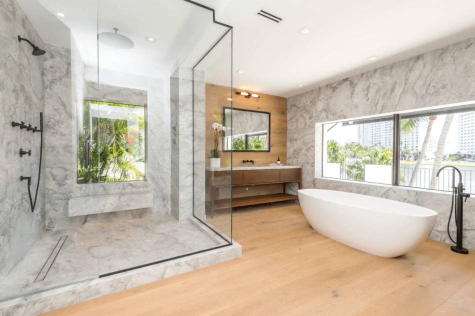 Contemporary bathroom with marble shower, wood vanity, and freestanding tub.