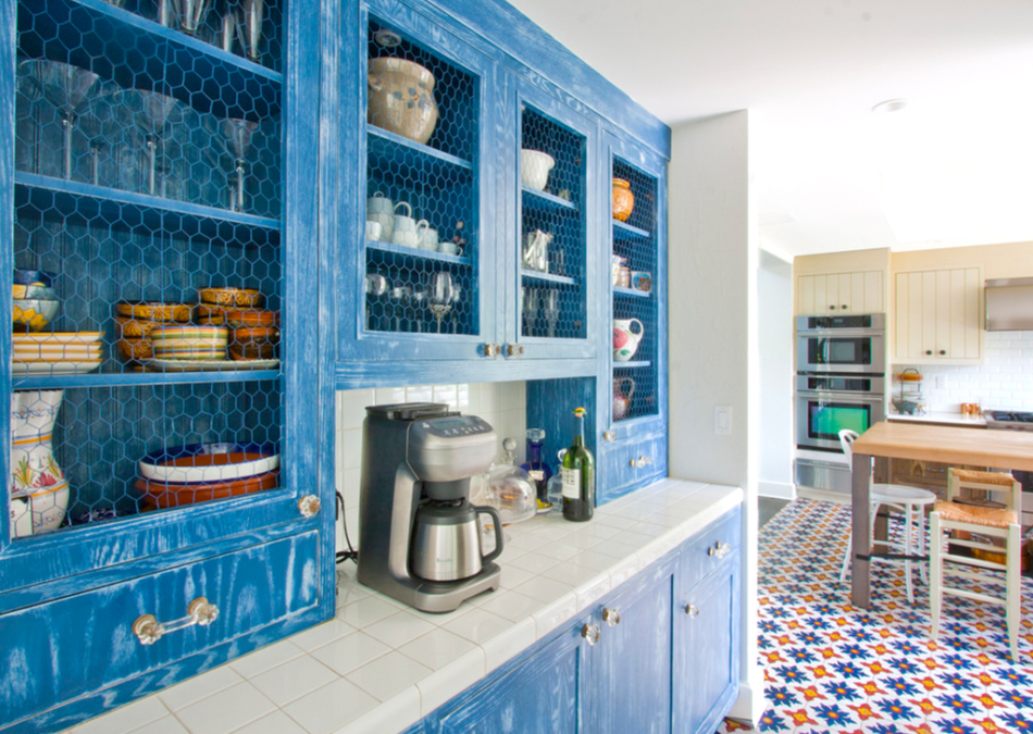 Bold blue kitchen cabinets with glass mesh doors and white tile counter.